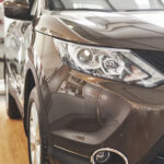 The headlights and the hood of a black luxury car.